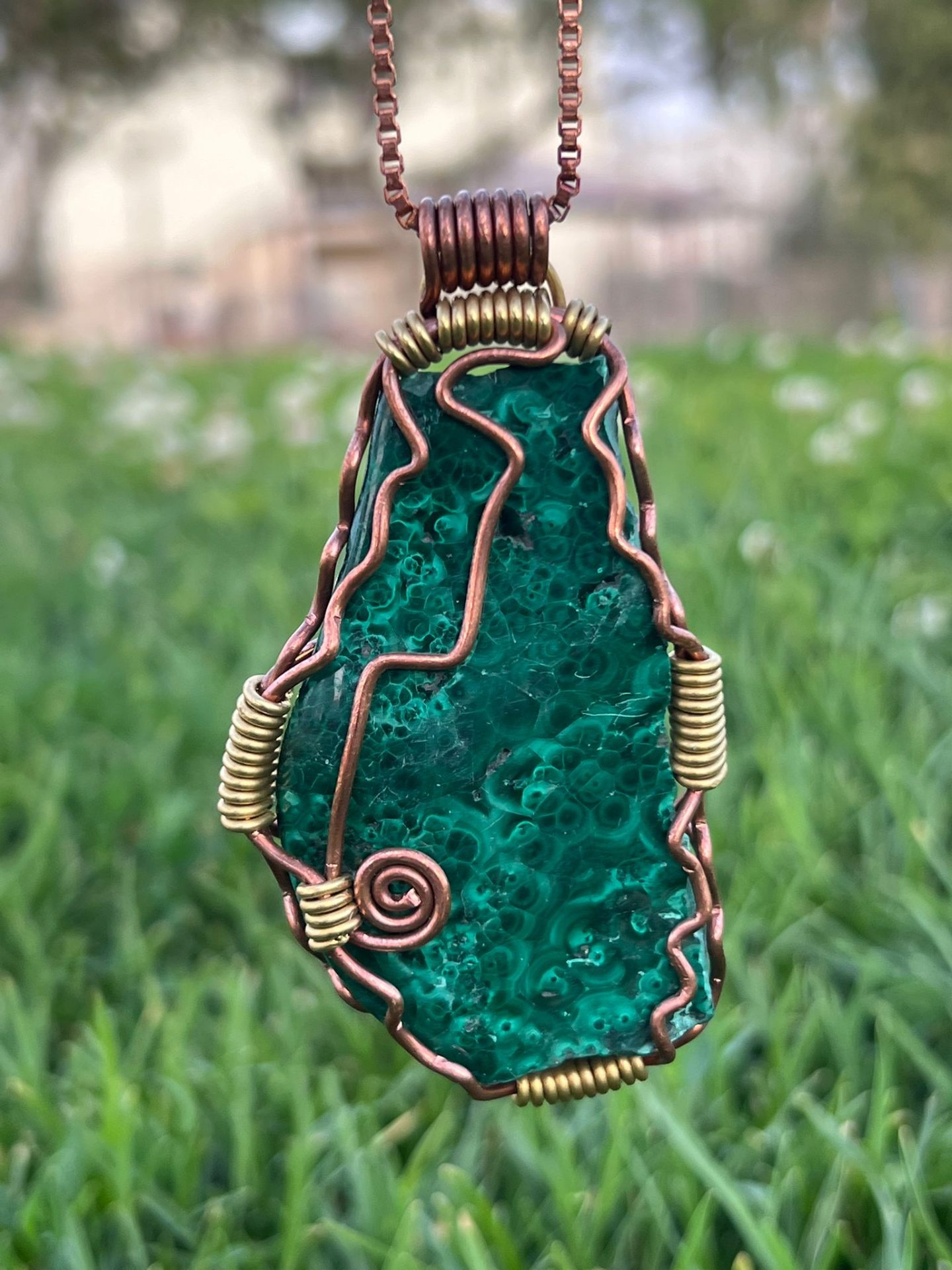 Large malachite pendant with rich emerald banding wrapped in copper